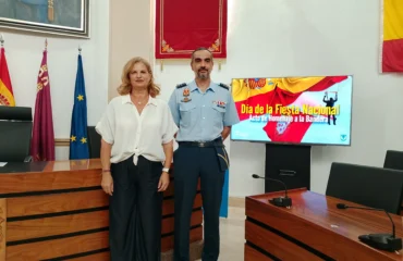 La alcaldesa de Alcantarilla, Paqui Terol y el coronel de la base posan junto al cartel que anuncia los actos para el 4 de octubre