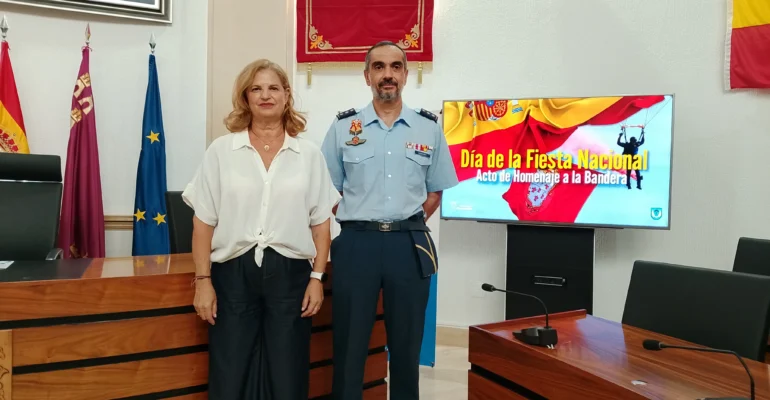 La alcaldesa de Alcantarilla, Paqui Terol y el coronel de la base posan junto al cartel que anuncia los actos para el 4 de octubre