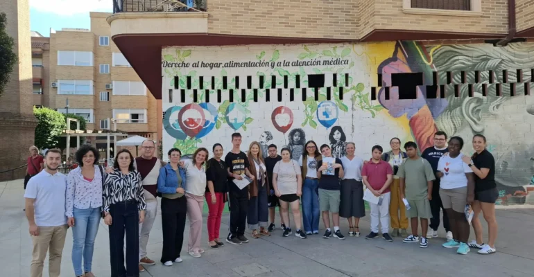 Miembros de la corporación municipal, la alcaldesa de Alcantarilla y la directora general de turismo, con alumnos del colegio Eusebio Martínez, posan delante de un grafíti